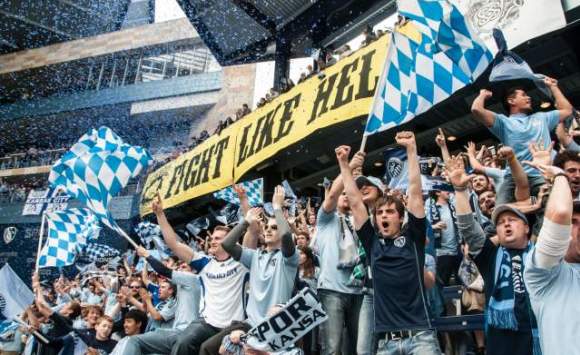 Image shows Sporting KC fans cheering with a sign that reads, "Fight like Hell."