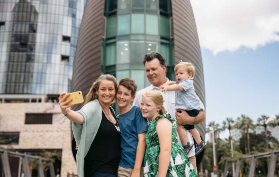 A family pose for a photo in front of The Bell Tower in Perth City