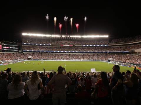Fireworks blasting over a stadium at night filled with people