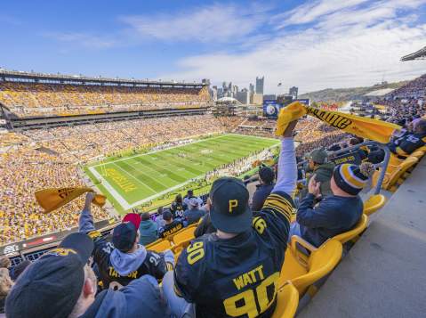 People in the stands of a football stadium waving yellow towels
