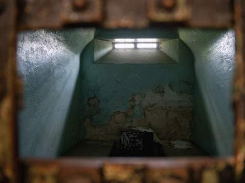 An old, eerie jail cell with a glowing window at the top