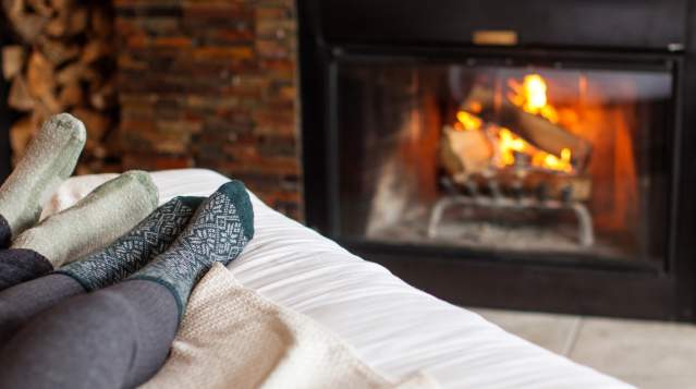 Two people relaxing in bed next to fireplace