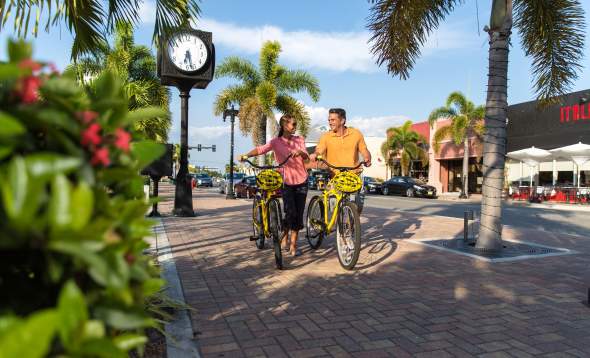 Man and woman walking yellow free loaner bikes in downtown Punta Gorda