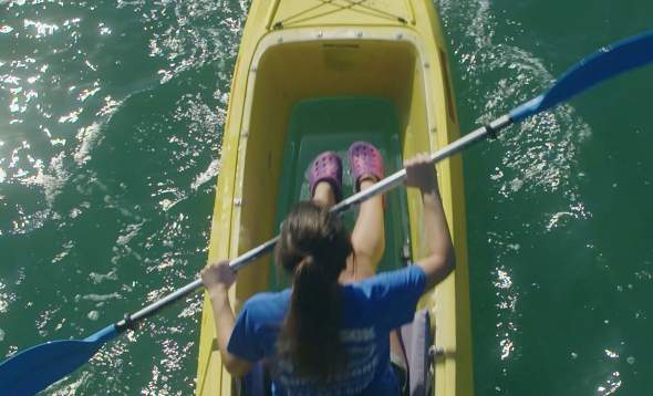 Top view of a woman paddling a glass-bottom kayak