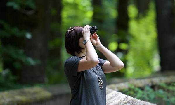 Woman looking through binoculars for birds in Beaumont