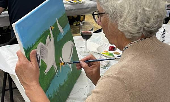 A woman carefully paints a whopping crane on a canvas at a class at the Port Aransas Art Center