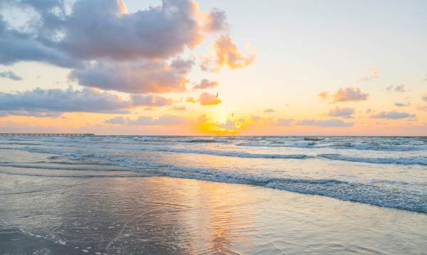 A bright, golden sunrise over the ocean waves on a beach in Port Aransas.