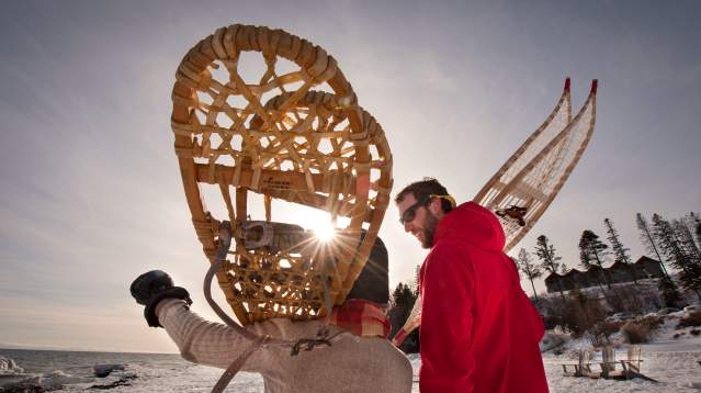 Two people with snowshoes over their shoulders carrying them