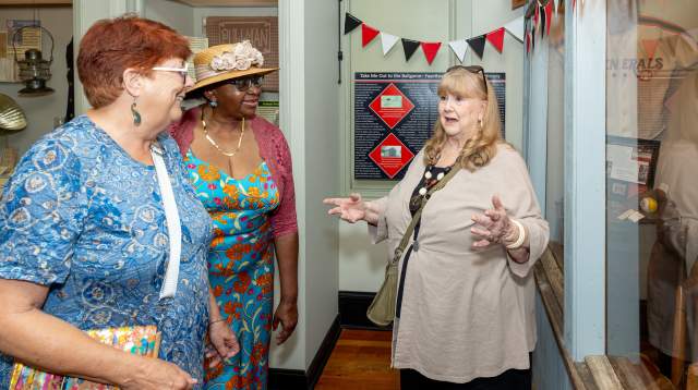 Three women chatting and laughing inside a local boutique, surrounded by colorful decor and display shelves.