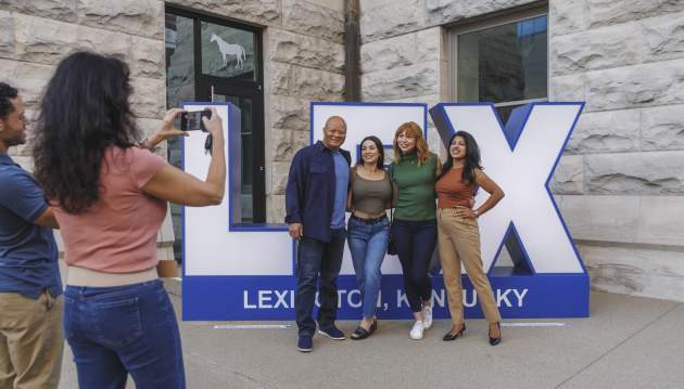 Group of people getting their picture taken in front of a LEX sign.