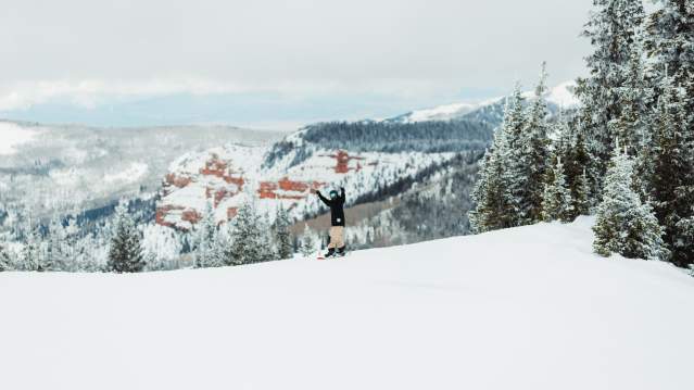 Snowboarding at Brian Head Resort with beautiful red rock in the background.