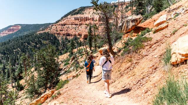 Hikers walk among red rock on the Cascade Falls Trail at Navajo Lake in Dixie National Forest.