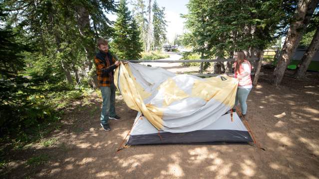 two people setting up a tent in the national parks