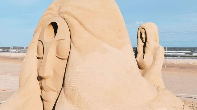 A large sand sculpture of a person's face resting on a hand at Texas SandFest.