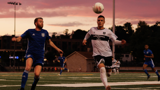 A Bavarian United SC player running after a ball with his opponent.
