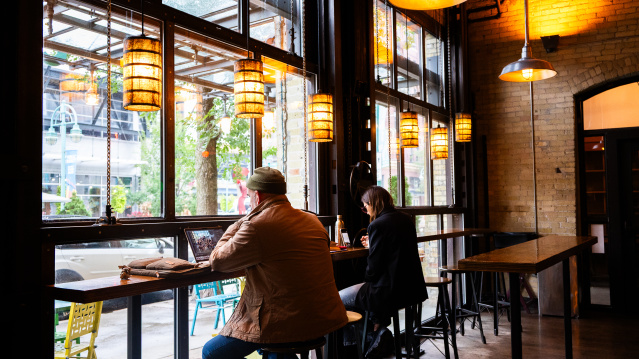 A man and a woman sitting by the window drinking coffee at Colectivo in the Historic Third Ward.