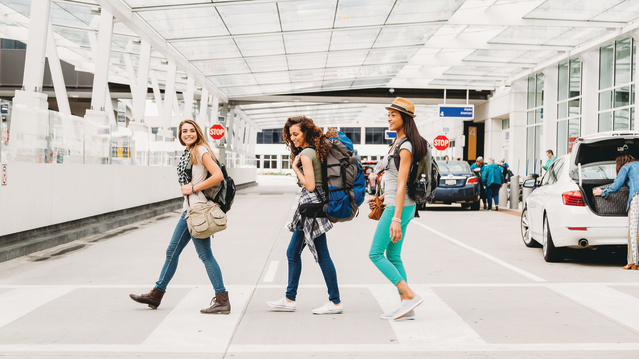 three women smiling after getting baggage and walking out of airport