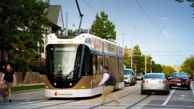 street car on road, cars and pedestrians passing