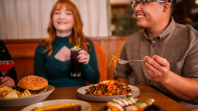 A diverse group enjoys a meal with various dishes and drinks at The Wolf restaurant