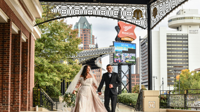 bride and groom holding hands, smiling, outside of Miller High Life Theatre