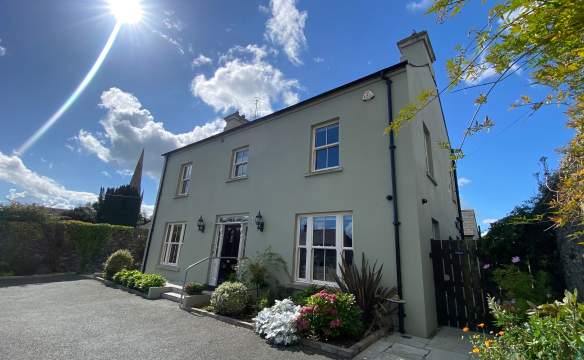 Exterior shot of Bramley House, a self-catering property in County Down.  There are plants outside the front of the house, and the sun is shining with blue skies.
