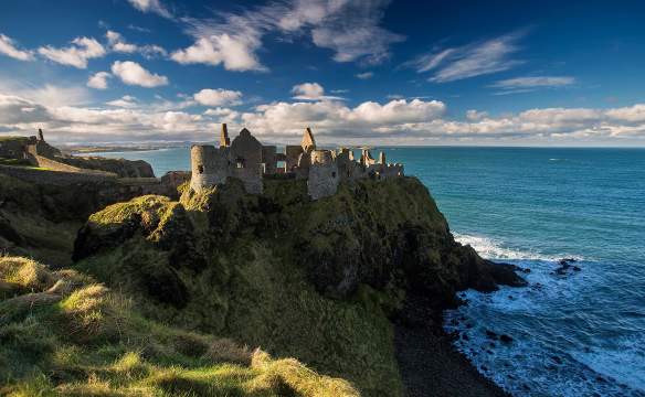 Medieval Dunluce Castle with blue skies.