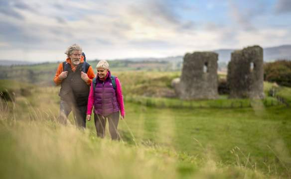 A couple enjoying a walk around the site of Harry Avery's castle with ruins in the background