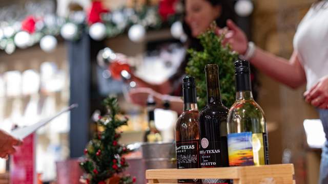 Image of woman pouring a wine sample at the Sipping Under the Stars event booth inside of Hamiltons shop downtown Brownwood.