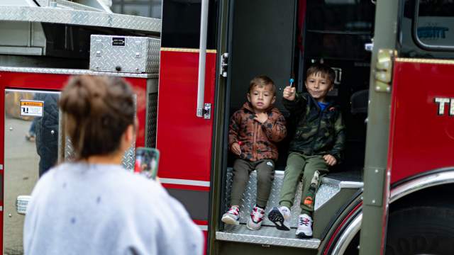 Kids sitting in a Fire Engine getting their picture taken.