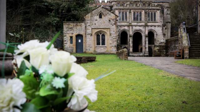 A view of flowers and the building to St Winefride's Well in the background