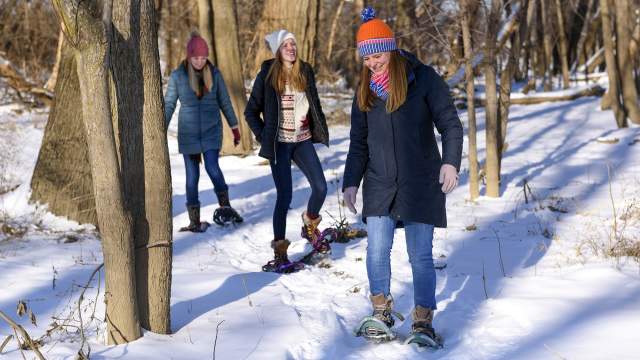 girls wearing snowshoes walking through the snow