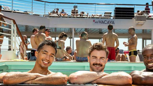 Four handsome men in a pool on board a cruise ship, smiling