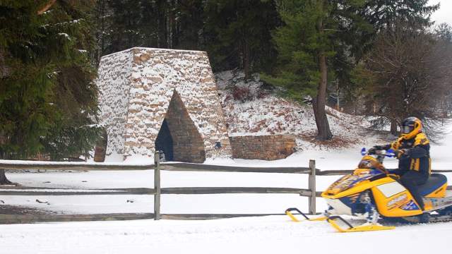 A snowmobiler enjoys the winter scenery at the site of a historical ironworks operation at Greenwood Furnace State Park