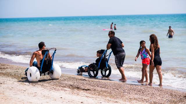 People use beach wheelchairs to enjoy the Lake Michigan on a sunny day