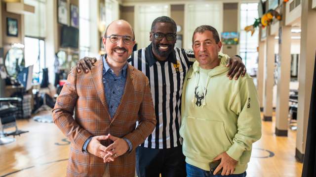 Three men standing together with arms around each other's shoulders at Gee's, smiling at the camera.