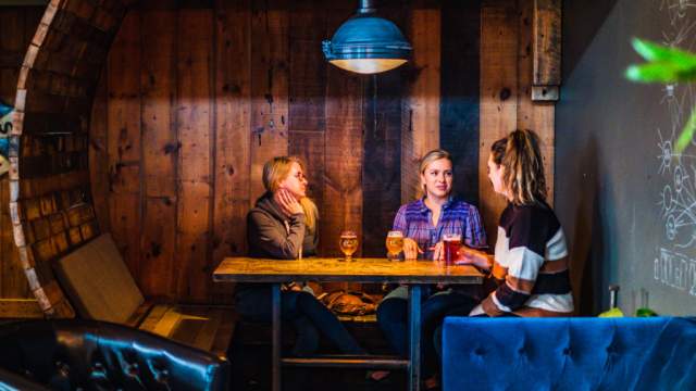 Three people sitting in a booth at Draft & Vessel in Wauwatosa