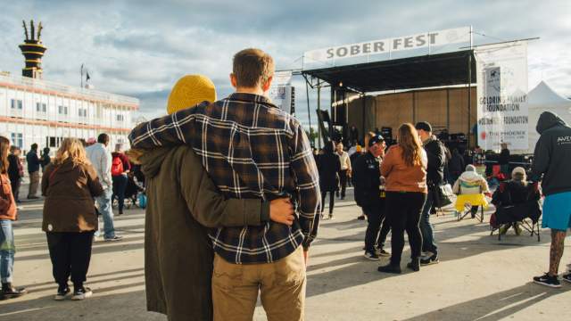 two people embrace in front of a stage at outdoor music festival