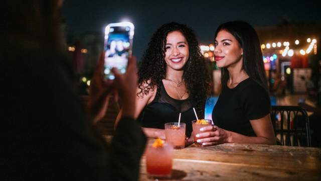 A woman takes a photo of two other women during a girls' night out in Orlando.