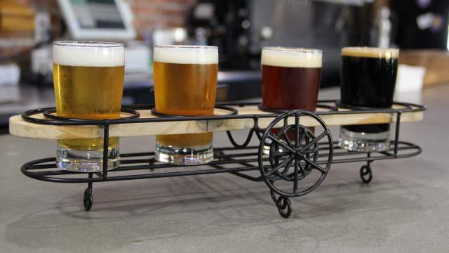 A flight of beer samples displayed apropros in wire-framed bi-plane-shaped holder at Crooked Can Brewing.