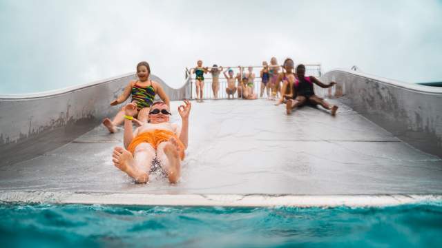 En gjeng med barn ned den store sklia på Østfoldbadets utebasseng