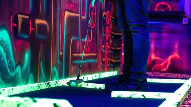 Person spiller minigolf glow på Sprett i Askim