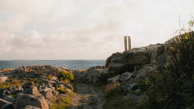 Sti ut mot havet og steinskulptur med to høyreiste steiner