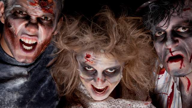Three people dressed as zombies posing with scary faces