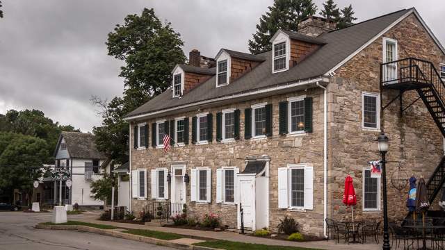 Exterior of an old stone home with white trimming turned restaurant with a fire escape on the side of the building