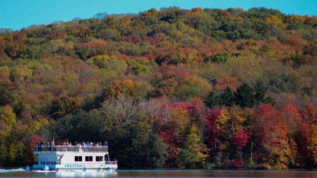 Pontoon boat on Lake Arthur will fall foliage-filled trees in the background