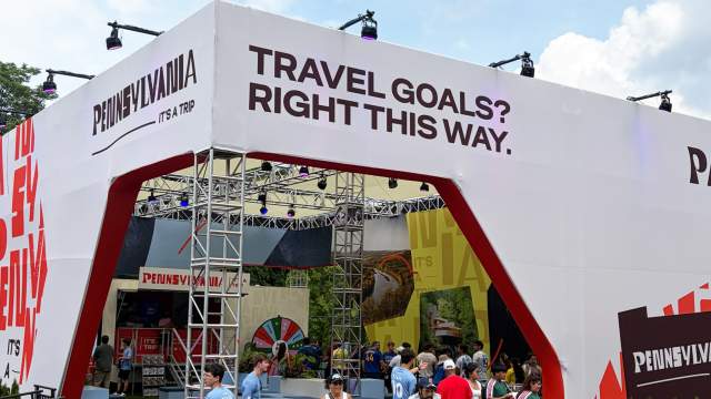 People walking in and out of an open-air pavilion that reads Travel Goals?Right This Way