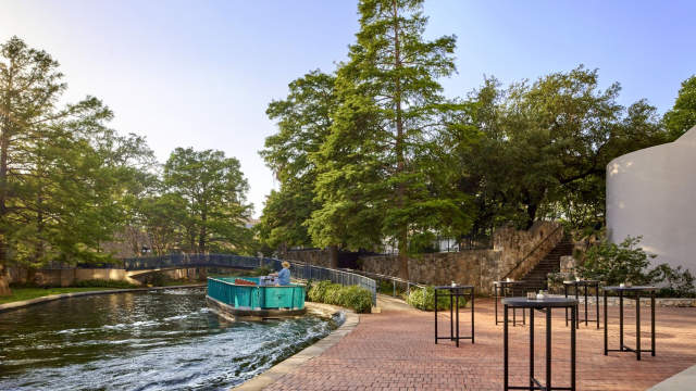 River barge floating along River Walk with large trees in background