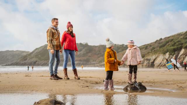 A family playing on swansea beach in the winter