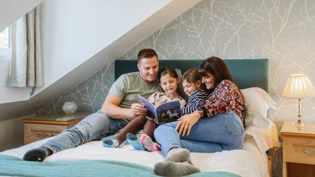 A family in bed reading a children's book