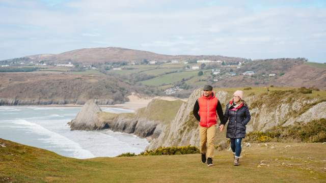 A couple walking across Three cliffs in the winter